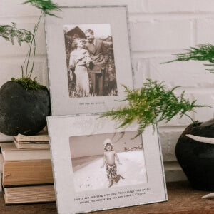 A photo frame with two pictures and a plant on a table.