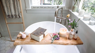 A serene bathroom scene with a wooden tray and lit candles placed on a bathtub, creating a cozy and relaxing ambiance.