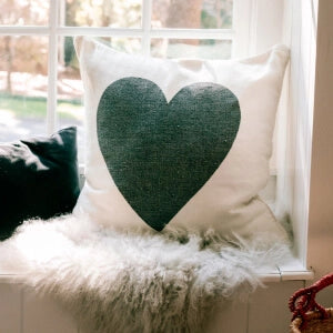 A heart-shaped pillow resting on a window sill, adding a touch of warmth and love to the serene view.