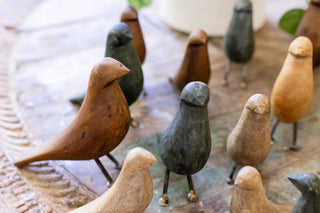 Wooden birds on a table with a vase of flowers - a charming display of decorative wooden birds alongside a vase filled with vibrant flowers.