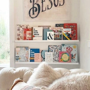 A white pillow rests on a couch next to a bookshelf.