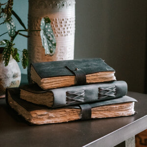 Books stacked on table with vase.