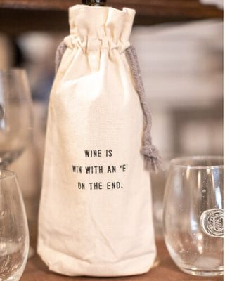 a white bag with a string on it next to a few wine glasses