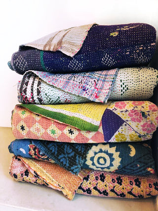 stack of 5 different kanthan quilts showing off the variations in colors and patterns