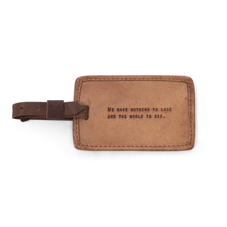 brown leather luggage tag with the quote "We have nothing to lose and the world to see."